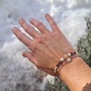 Hand mit Perlenarmband und Heilstein